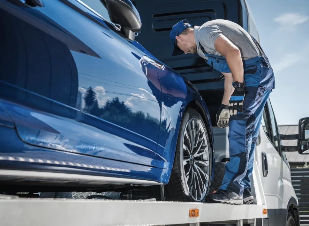 tow truck driver loading a car on a tow truck